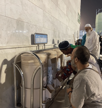 muslim man drinking water from the zamzam well in saudi arabia
